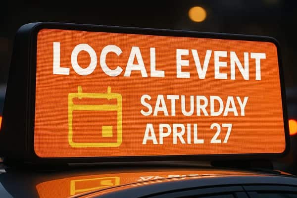 A smiling veterinarian in blue scrubs gently comforts a large dog on an exam table inside a clean, modern veterinary clinic.